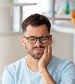 Man with glasses experiencing toothache